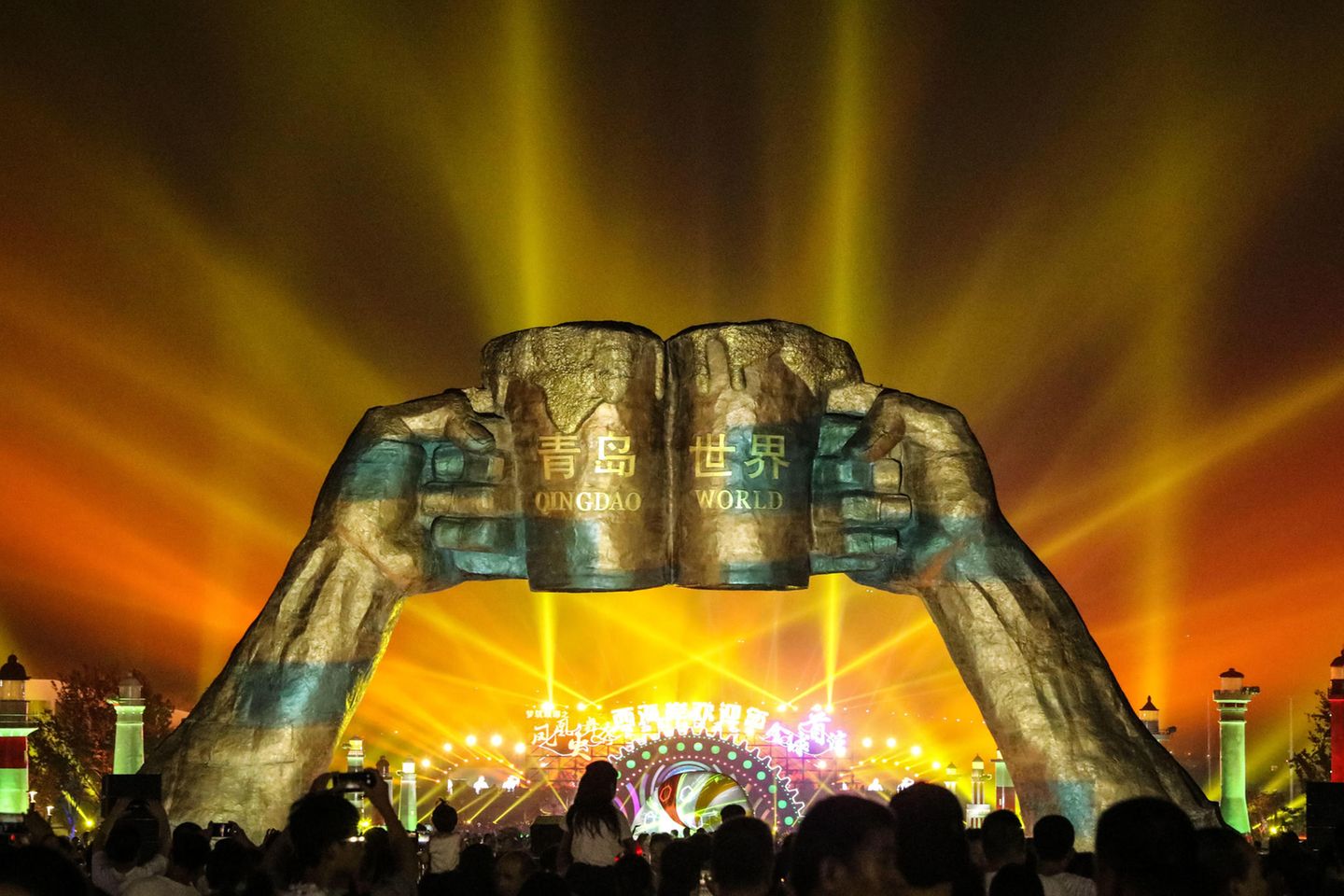 Chinas Oktoberfest: Das Bierfest in Qingdao Zwei riesige, goldene Bierkrüge werden von zwei Händen in die Luft gestemmt