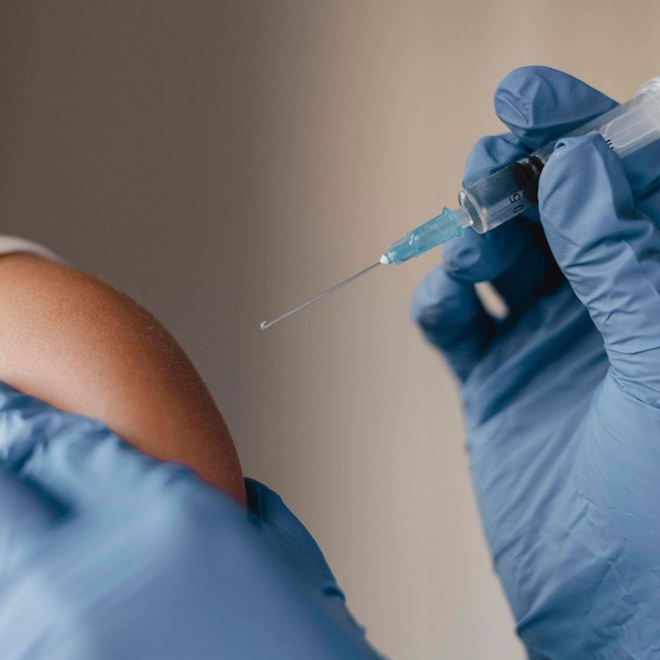 Ein Arzt impft ein Kind gegen die Grippe