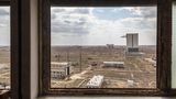 Durch ein Fenster sieht man auf die kasachische Steppenlandschaft mit weißen Gebäuden.
