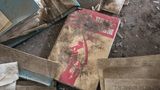 Ein Buch im Dreck unter Dreck auf dem Fußboden. Hammer und Sichel in Rot.