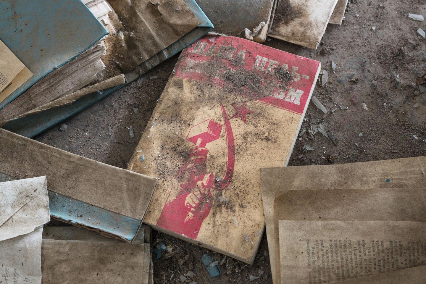 Ein Buch im Dreck unter Dreck auf dem Fußboden. Hammer und Sichel in Rot.