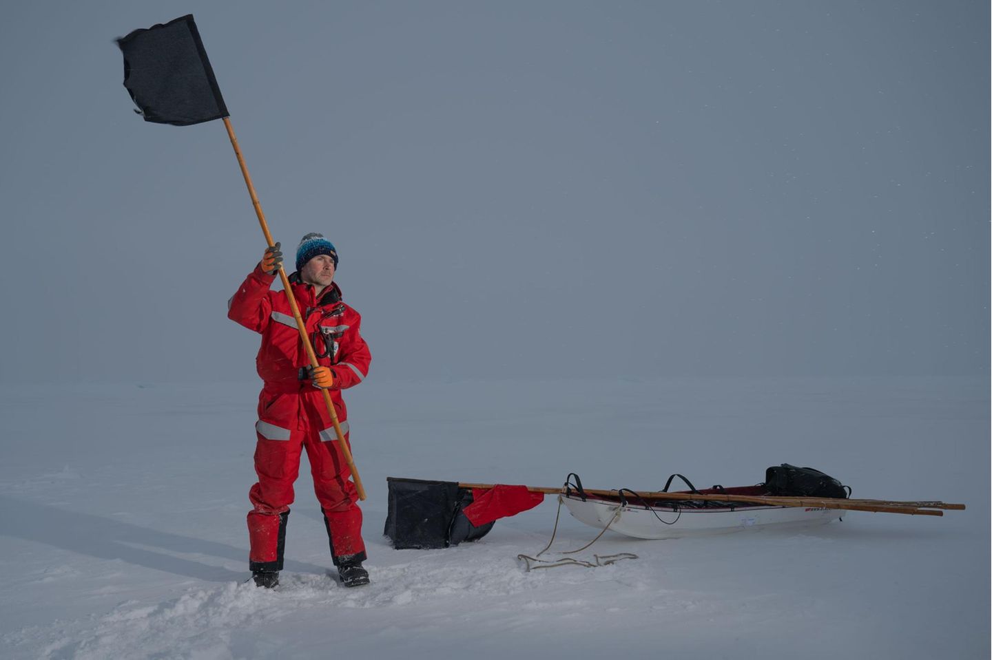 Aufbruchstimmung am Nordpol Ein Mann hält eine schwarze Flagge in der Hand