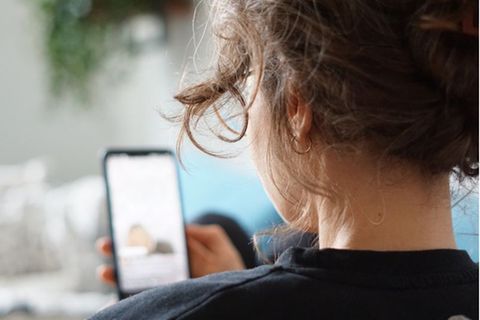 Eine Frau schaut auf Ihr Smartphone