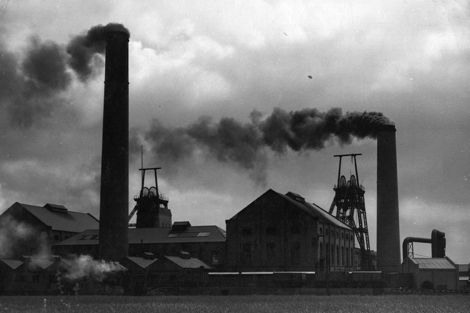 Rauch steigt aus den Schornsteinen eines Kohlebergwerks auf. Ca. 1950