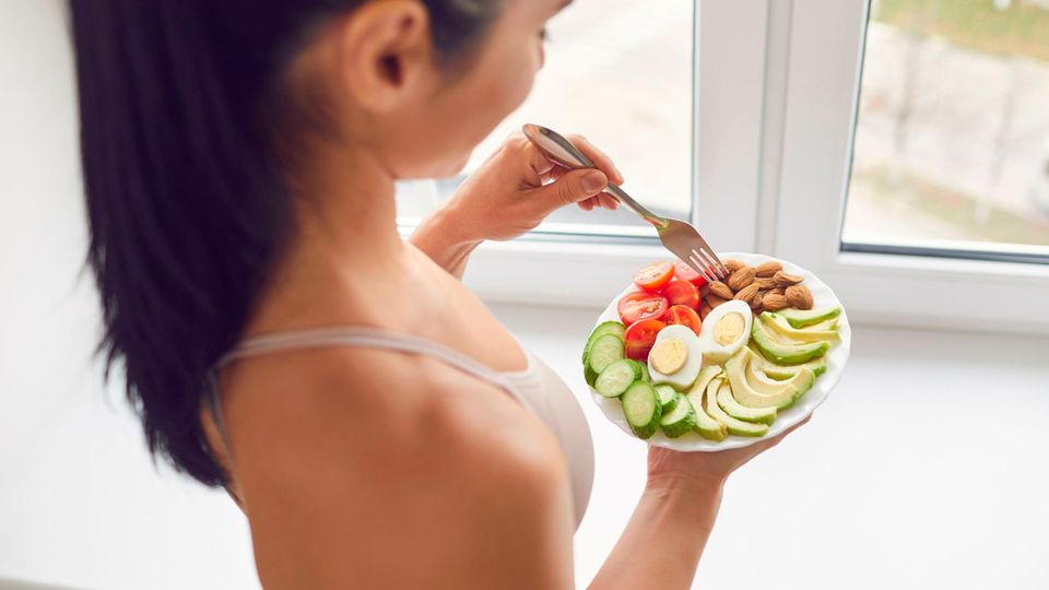 Frau isst vegetarischen Salat, schaut auf Teller Frau isst vegetarischen Salat, schaut auf Teller
