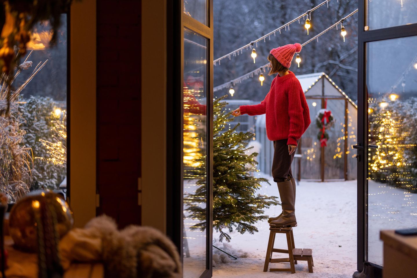 Frau schmückt den Garten weihnachtlich