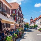 Menschen sitzen im Außenbereich eines Restaurants und genießen ihr Essen bei Sonnenschein