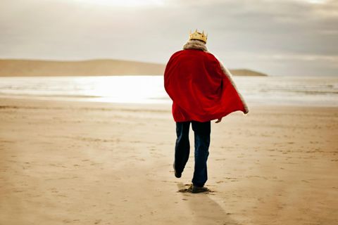 Ein Mann der gekleidet ist wie ein König spaziert am Strand