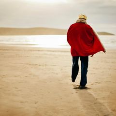 Ein Mann der gekleidet ist wie ein König spaziert am Strand