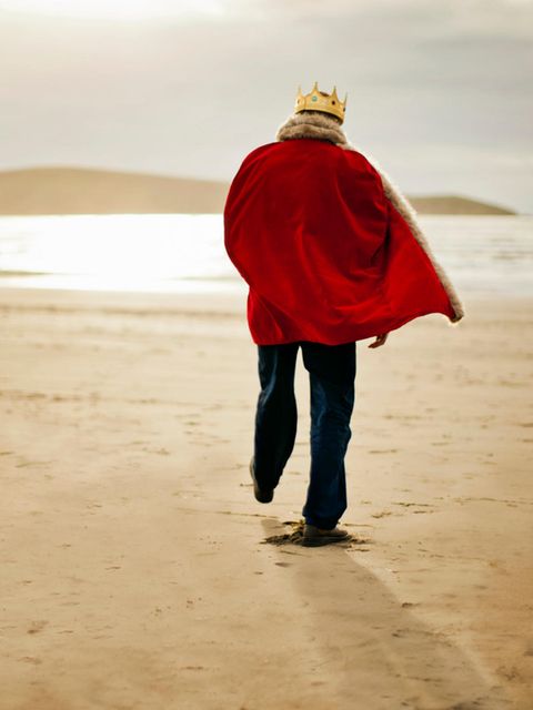 Ein Mann der gekleidet ist wie ein König spaziert am Strand