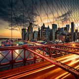 In der Abenddämmerung entsteht ein geometrisches Muster aus kantigen Gebäuden, Brückenstreben und den Gitternetzen der berühmten Hängebrücke über den East River. Die Lichter der vorbeiziehenden Autos verwandeln sich in Lichtstreifen. Rund 120.000 Fahrzeuge queren das Bauwerk täglich