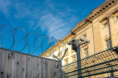 Gefängnismauer mit Stacheldraht unter blauem Himmel