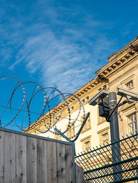 Gefängnismauer mit Stacheldraht unter blauem Himmel