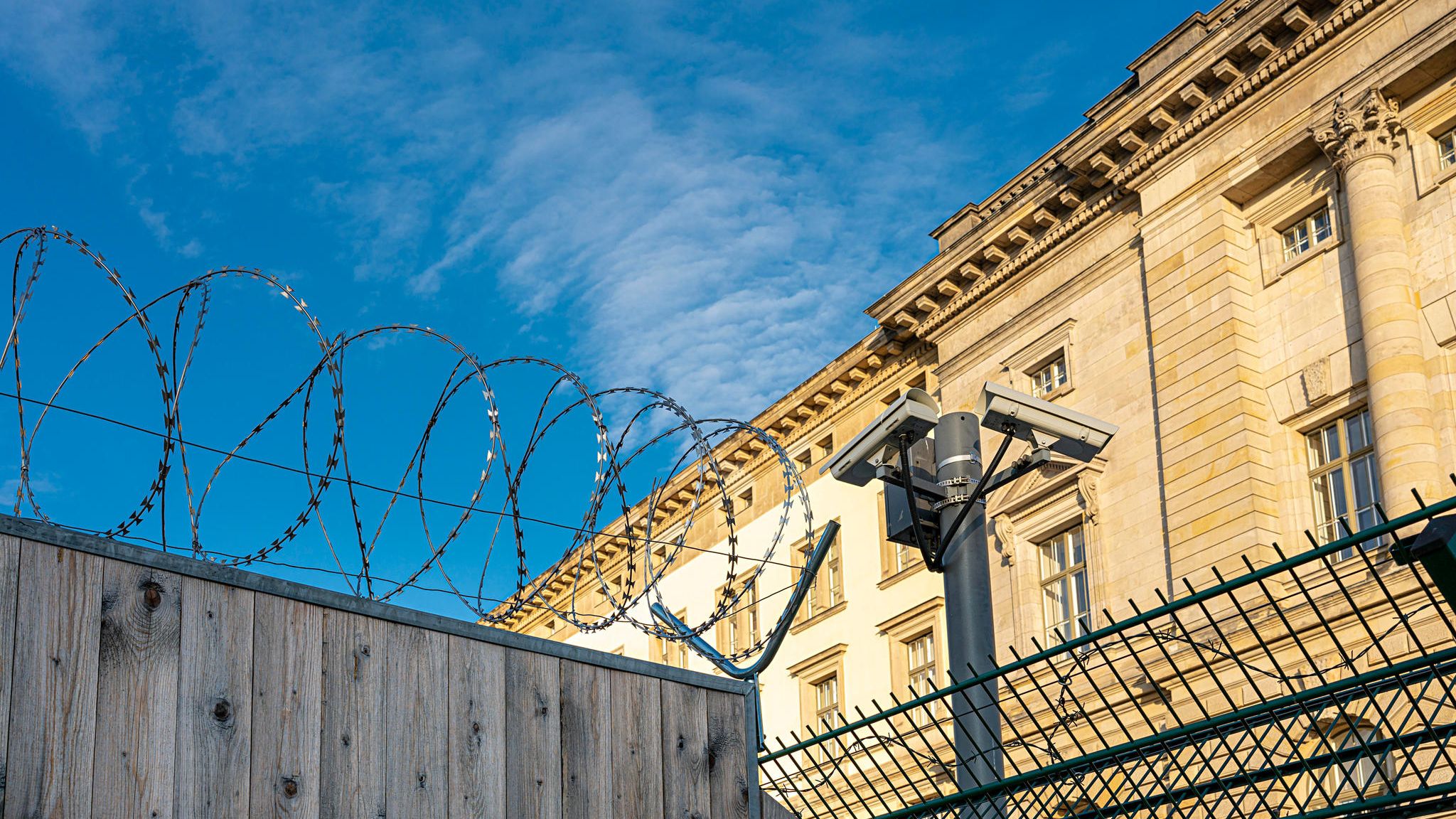 Gefängnismauer mit Stacheldraht unter blauem Himmel