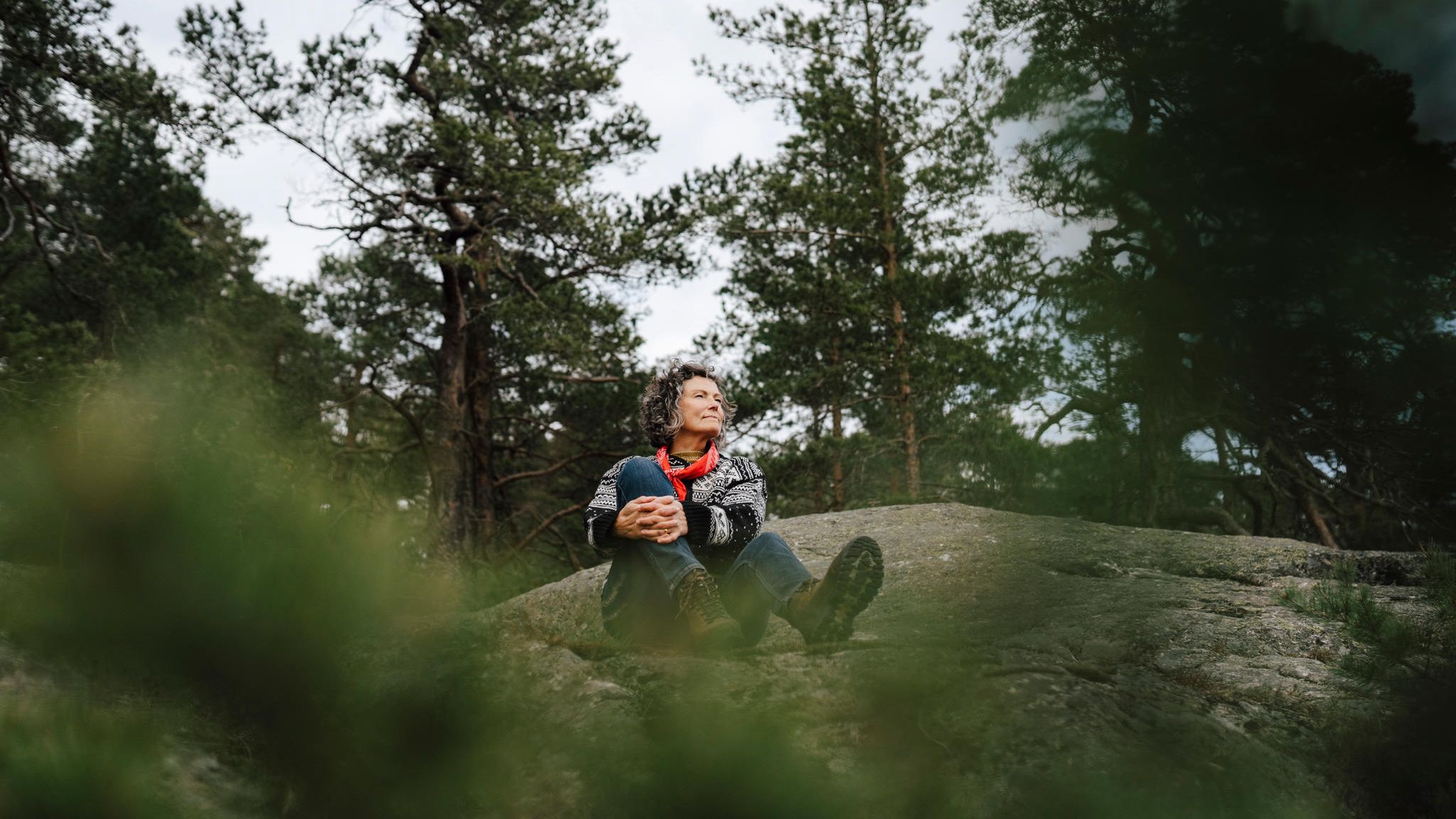 Eine Frau sitzt auf einem Felsen im Wald