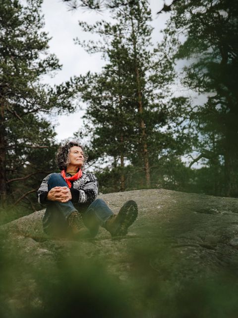 Eine Frau sitzt auf einem Felsen im Wald