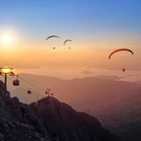 Blick von einem Berg aus auf Paraglider in Abendstimmung