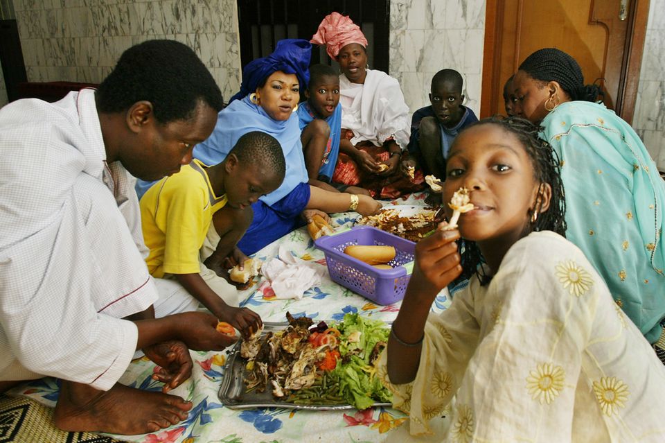 eine Familie beim Essen mit der Hand und auf dem Boden