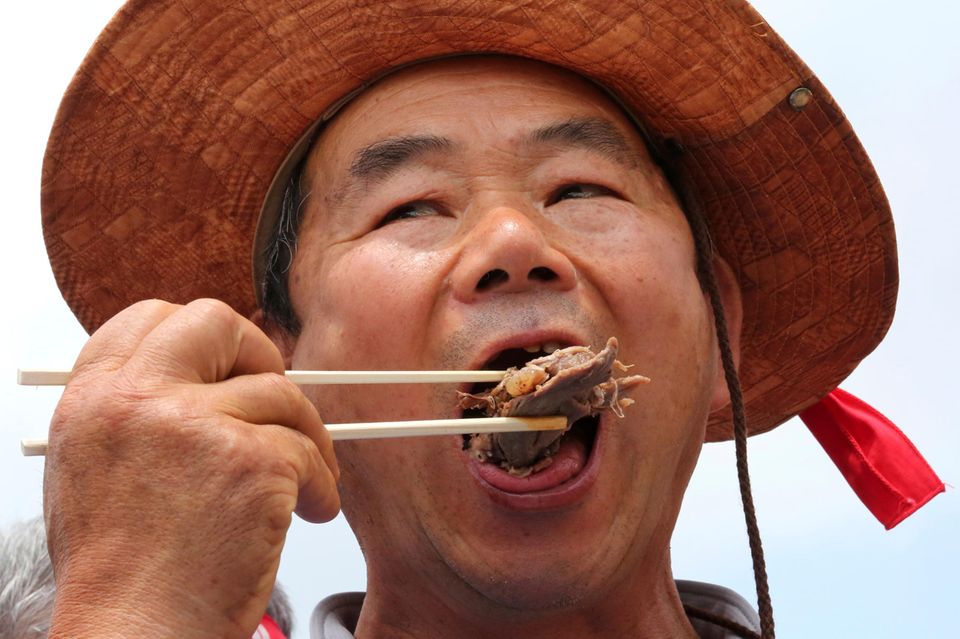 Ein Mann isst ein Stück Fleisch mit Stäbchen