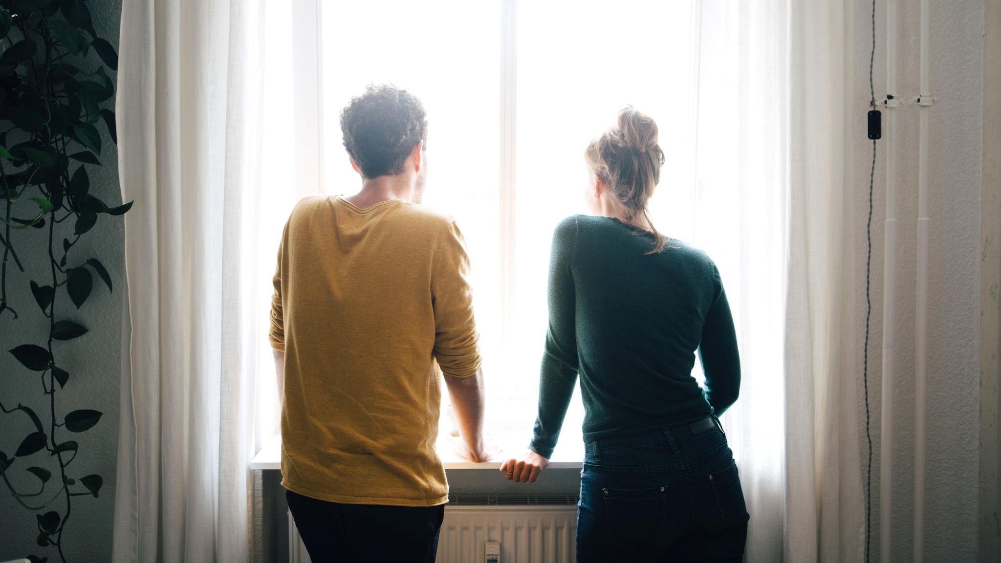 Junges Paar schaut aus dem Fenster Junges Paar schaut aus dem Fenster