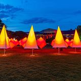 Beleuchtete künstliche Bäume stehen vor einem alten Gebäude.