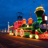 Ein festlich beleuchteter Touristenzug (man sieht die Lok) auf der Straße.