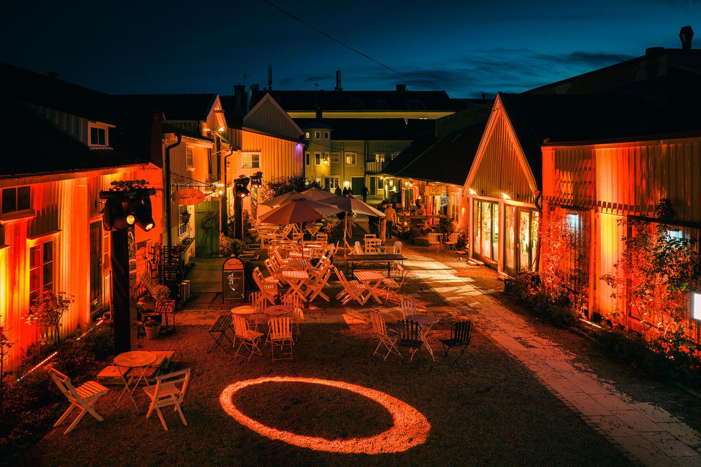 eine Gasse aus schwedischen Holzhäuser mit Holzsstühlen vor der Tür, bei Nacht, rot beleuchtet