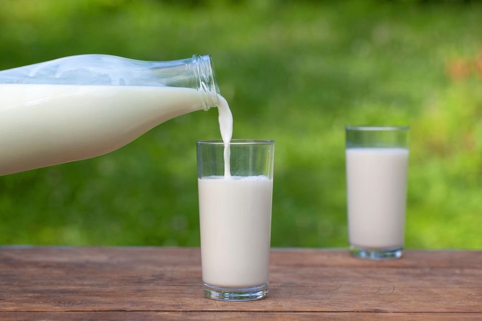 Milch wird aus einer Flasche in ein Glas gegossen. Ein zweites Glas steht daneben