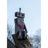 Auf einem Baumstumpf sitzt ein selbst gebastelter Roboter.