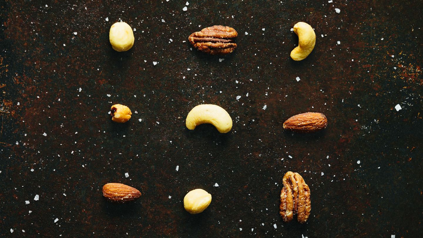 Verschiedene, mit Salz bestreute Nüsse liegen einzeln auf einem Blech Verschiedene, mit Salz bestreute Nüsse liegen einzeln auf einem Blech