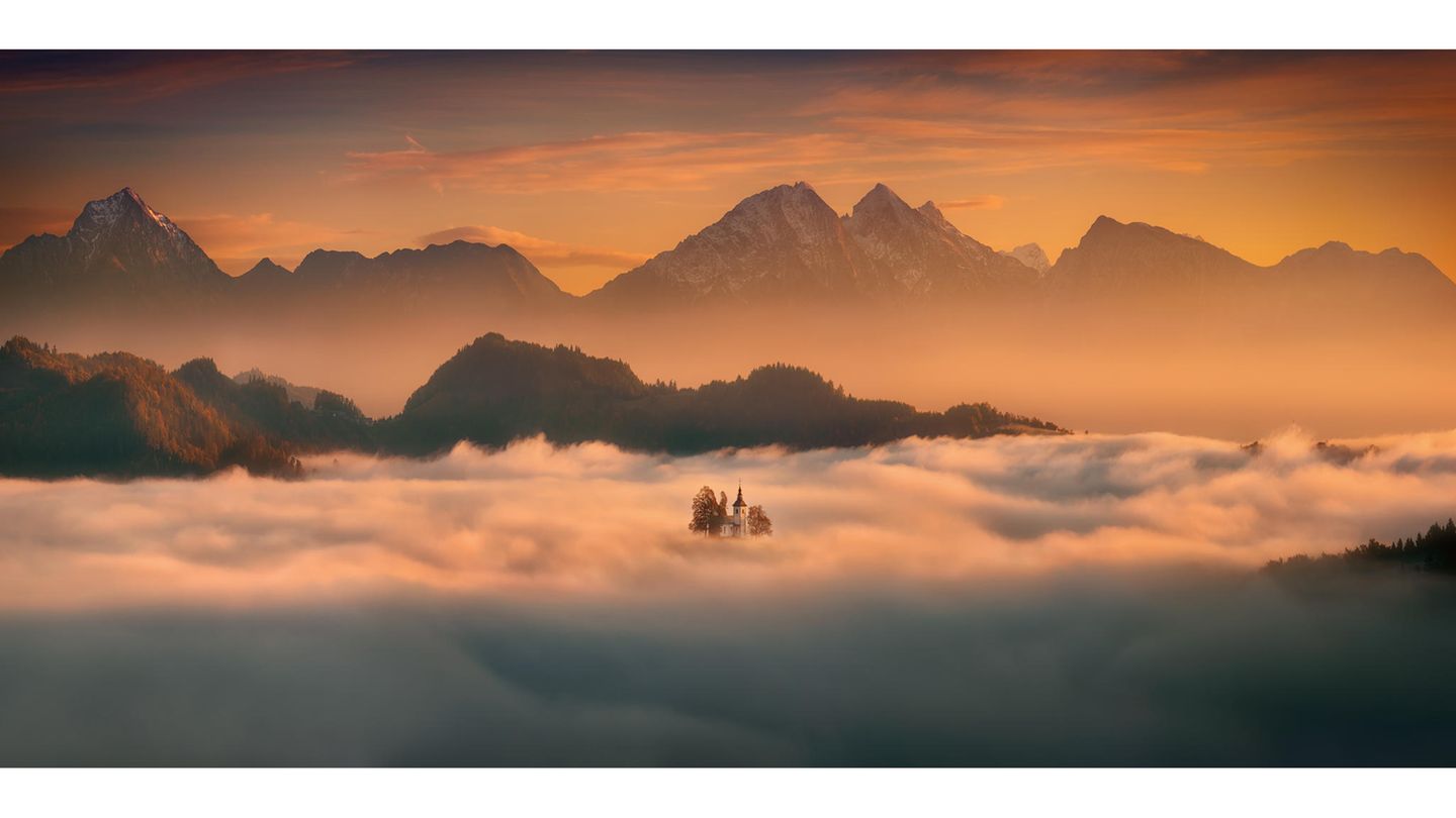 Landschaftsbild einer aus dem Nebel ragenden Kirche