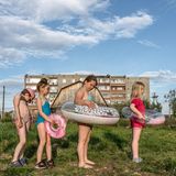 Vier Kinder in Schwimmkleidung auf einer Wiese vor einem Haus