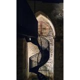 Wendeltreppe im Dunkeln, angeleuchtet das byzantinische Kreuz an der Wand.