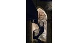 Wendeltreppe im Dunkeln, angeleuchtet das byzantinische Kreuz an der Wand.