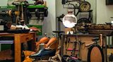 Nähmaschine, Bilder von Schuhen, auf dem Tisch alte Schuhe.