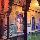 Schwimmbecken mit maurisch dekorierten Säulen und bunten Kacheln.