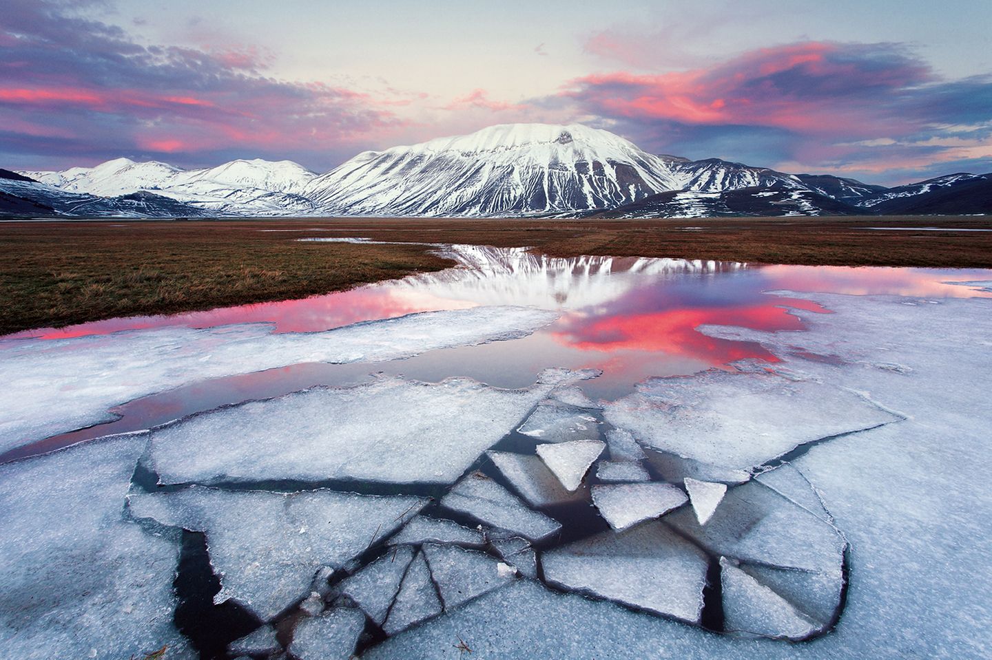 It’s Showtime! Im Sommer sind Blütenmeere aus Mohn, Kornblumen und Margeriten die Hauptakteure von Castelluccio; bis schmelzender Schnee die Hochebene überschwemmt. Begleitet von pinkfarbenen Lichtern haben nun die Sibillinischen Berge ihren großen Auftritt: Im Wasser sieht man sie doppelt