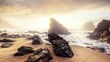 Trügerisch ruhig gibt sich das Meer an diesem Abend am Praia da Adraga. Weil der raue Atlantik das Schwimmen meist unmöglich macht, hat der traumhafte Strand in Portugals Westen bislang nur unter Locals hohe Wellen geschlagen: Sie treffen sich zum Sonnenbaden und Surfen