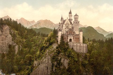 Schloss Neuschwanstein: Ein weißes Schloss auf einem Felsvorsprung mit Türmchen, spitzen Dächern, Erkern