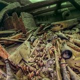 Dutzende schneckenförmige Geigenhälse liegen nebeneinader zwischen Balken und Brettern