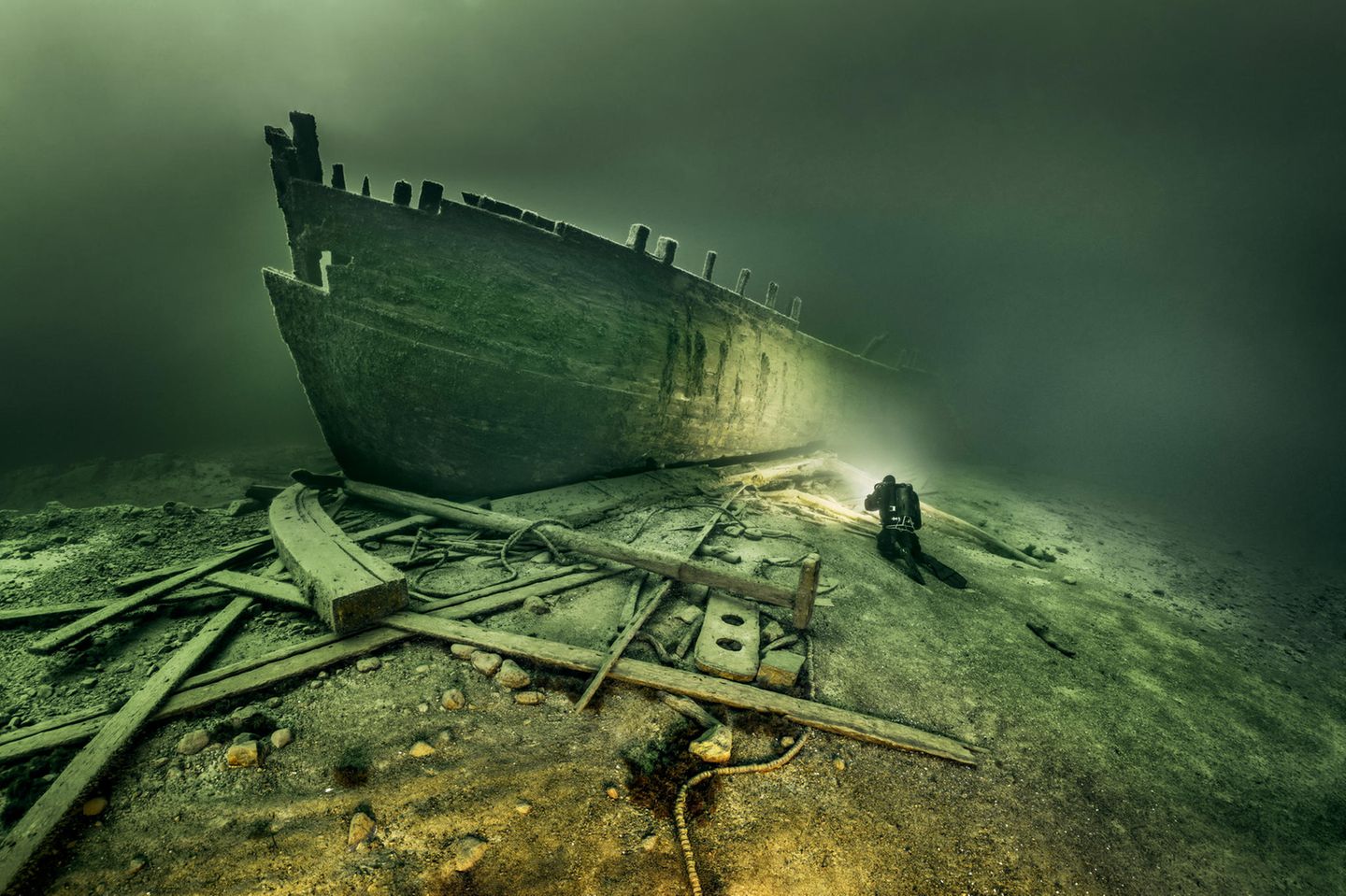 Abgerutscht und dennoch aufrecht Eine Schiffswand unter Wasser im Licht eines Tauchers