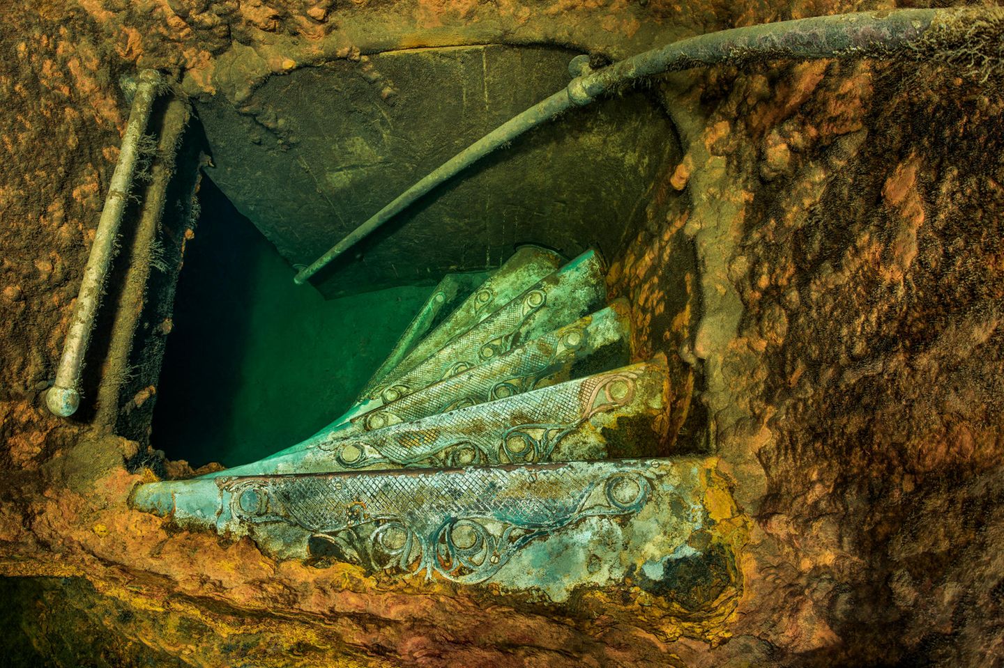 Treppe in den Untergrund Sechs grün schimmernde schmale Stufen einer Wendeltreppe von oben gesehen