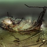 Fast zerfallenes hölzernes Schiffswrack ohne Deck, dessen Pinne rechts in die Höhe ragt