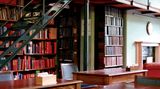 Tische, eine Treppe fürhrt auf eine Galerie, viele, viele Bücherregale