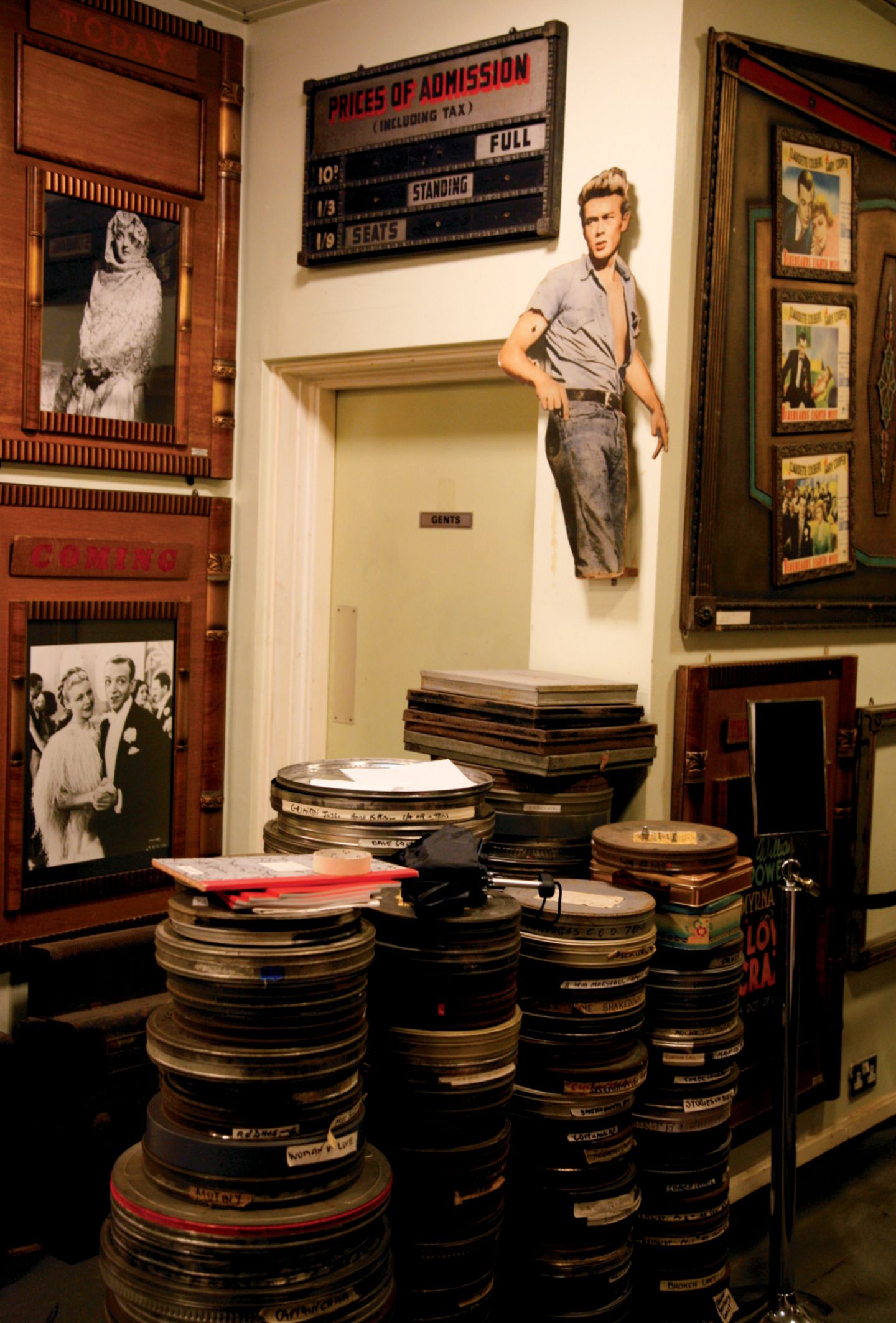 Cineastische Zeitreise: Cinema Museum Mehrere Stapel mit alten Filmrollen in Blechbüchsen, an der Wand alte Filmbilder unter anderem James Dean.