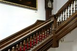 Treppe aus Holz mit historischer Standuhr und altem, großem Ölgemälde.