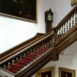Treppe aus Holz mit historischer Standuhr und altem, großem Ölgemälde.