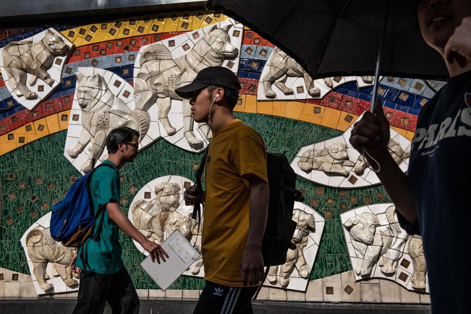 Menschen gehen in Tokio vor einem Wandbild von Hachiko vorbei