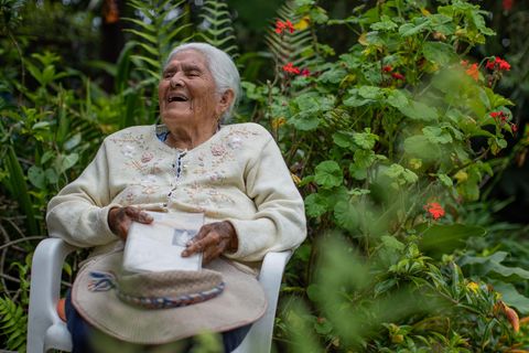 Die 98-jährige Maria Esther Varela sitzt lachend im Garten