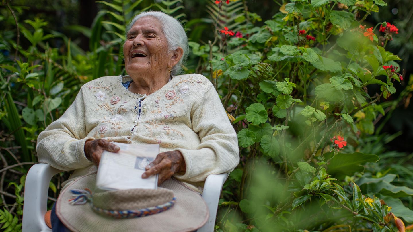 Die 98-jährige Maria Esther Varela sitzt lachend im Garten